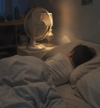 Child sleeping peacefully in a bedroom on a hot night with a fan and light bedding